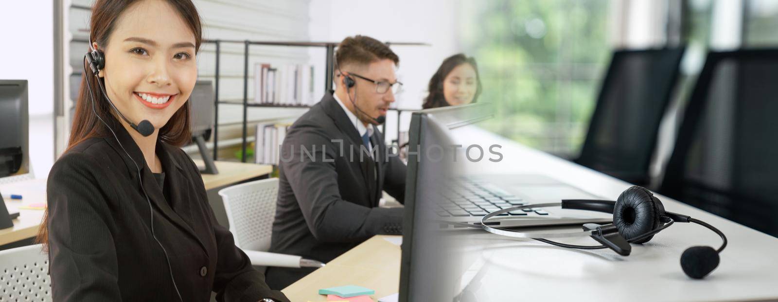 Business people wearing headset working in office to support remote customer or colleague. Call center, telemarketing, customer support agent provide service in broaden view .