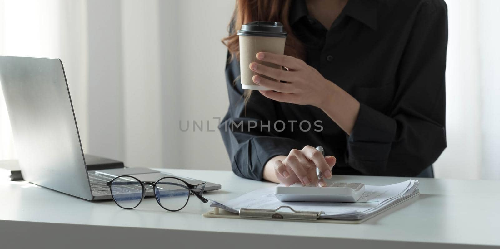 Close up Businesswoman hold coffee and using calculator finance, tax, accounting, statistics and analytic research concept.