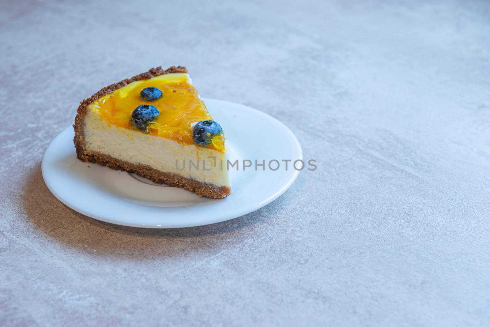 Piece of homemade cake on unusual plate shape with berry decorate on top