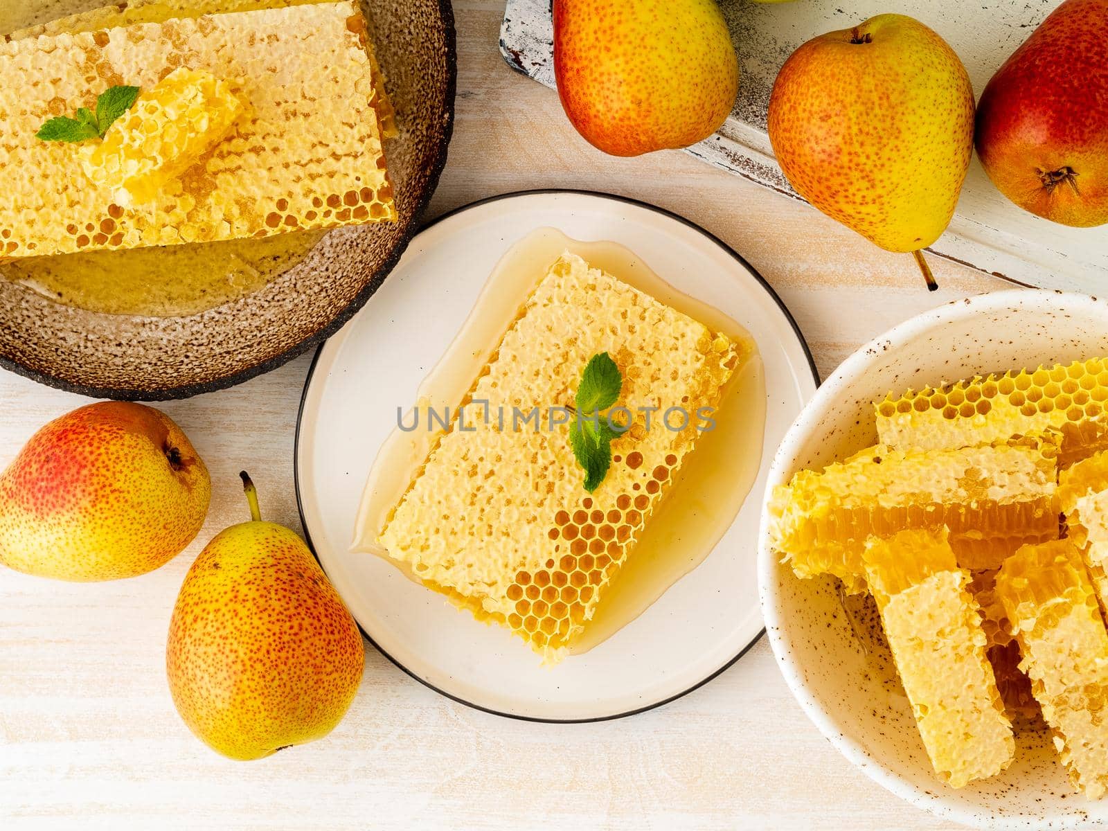 honey in honeycomb, close-up, on brown ceramic plate, on white wooden rustic table, top view. by NataBene