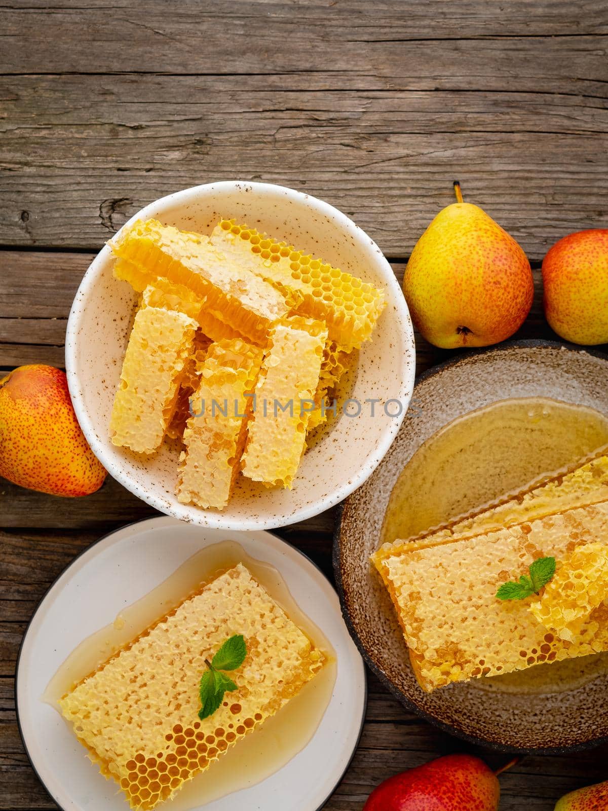 honey in honeycomb, close-up, on a brown ceramic plate, on old gray wooden rustic table, top view, vertical, copy space