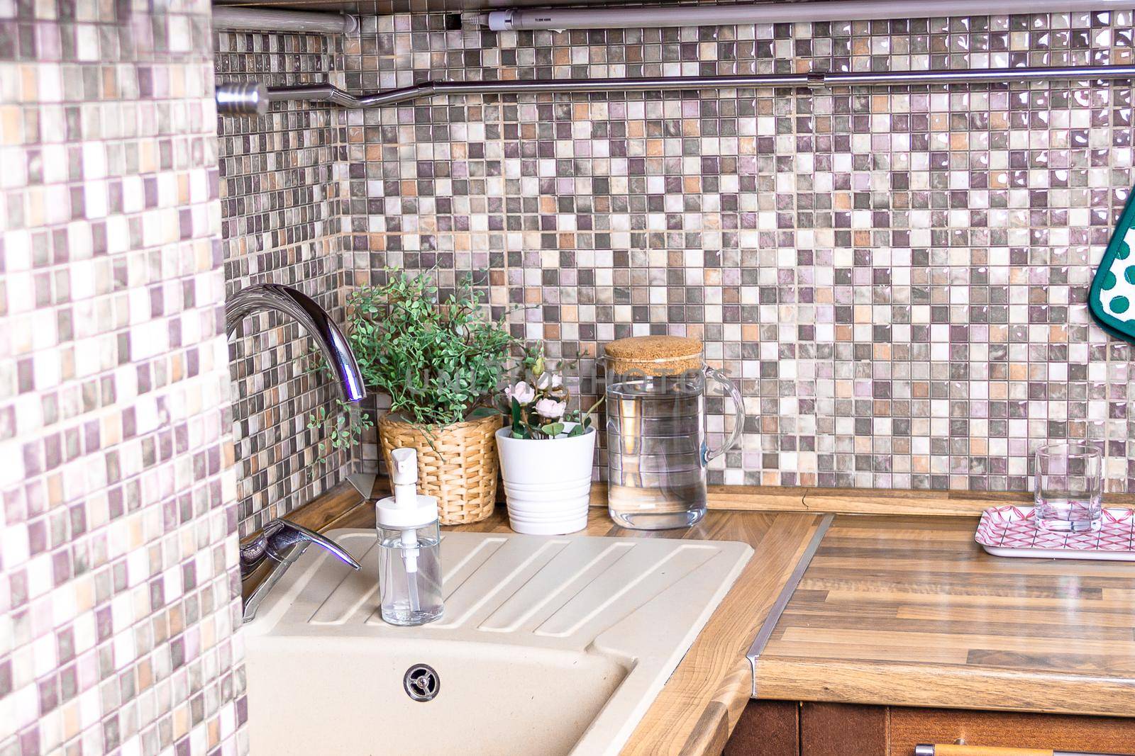 Brown wooden kitchen sink with plants and water.