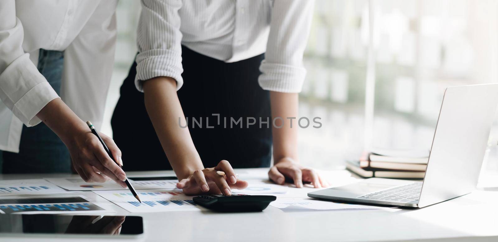 Businessmen use a calculator to calculate company financial statements for their colleagues, view and jointly solve problems within the company. Business finance and accounting concepts.