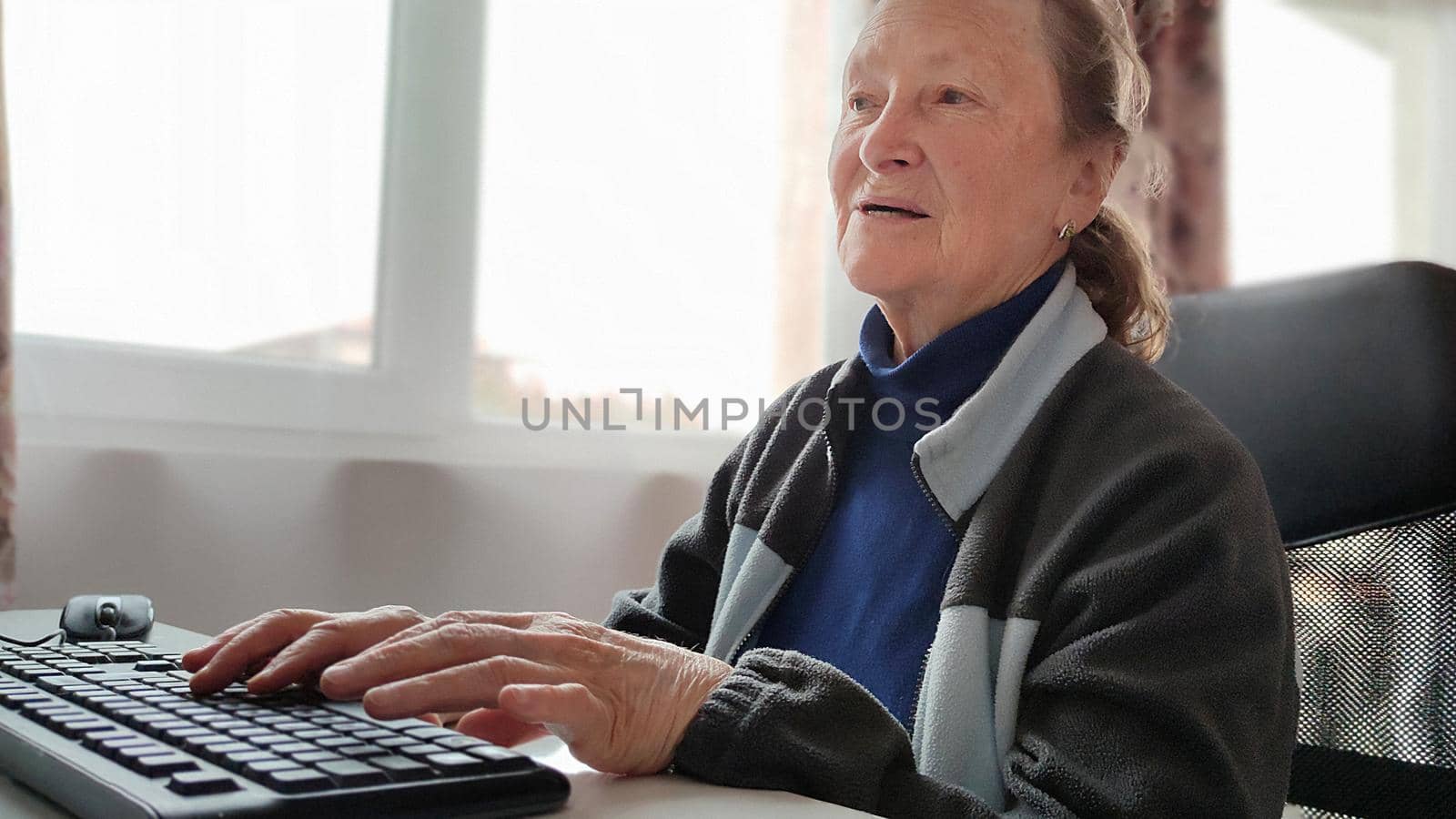 elderly woman working at home at the computer by Annado