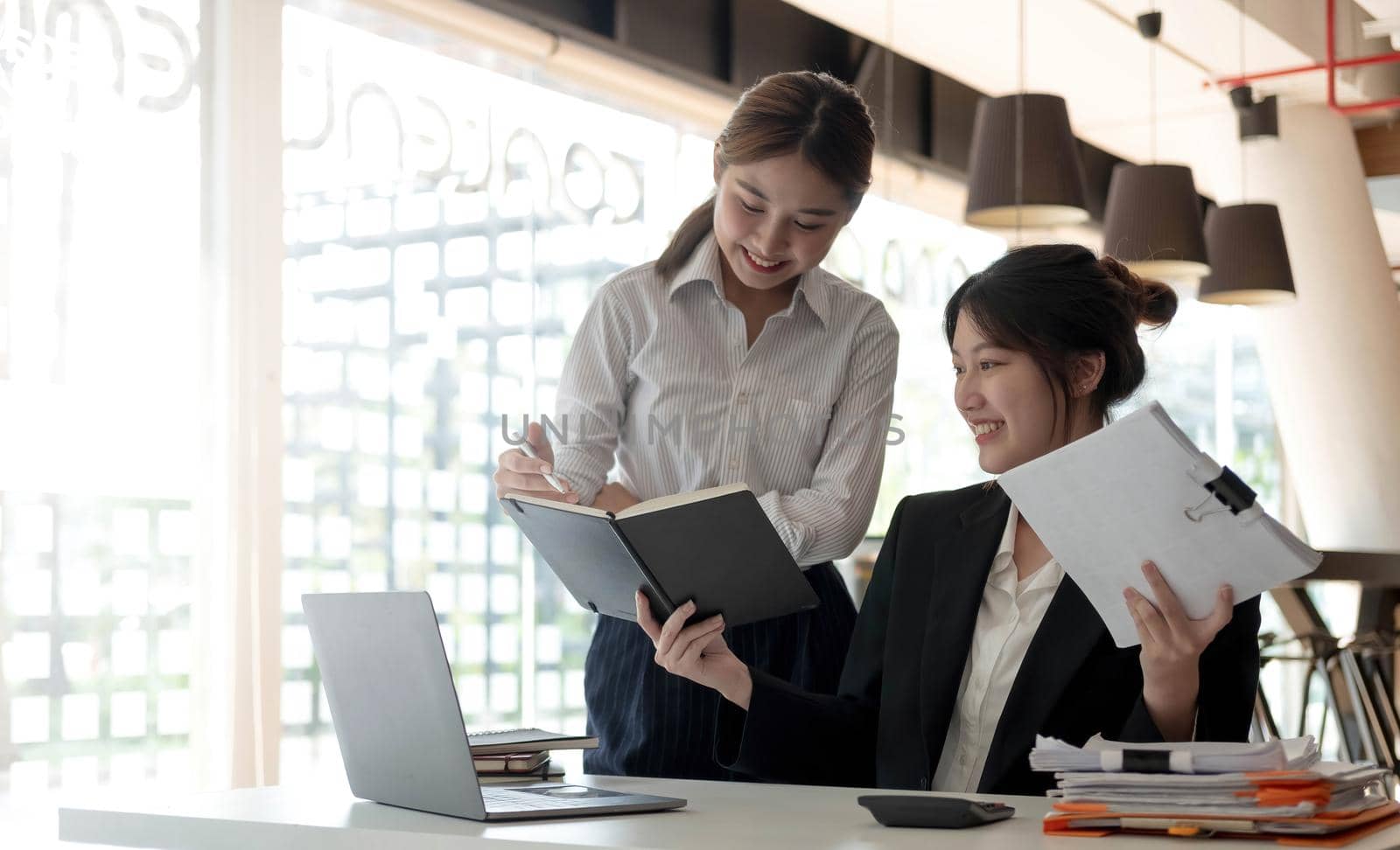 Two beautiful business people working together using a tablet at a modern office. by wichayada