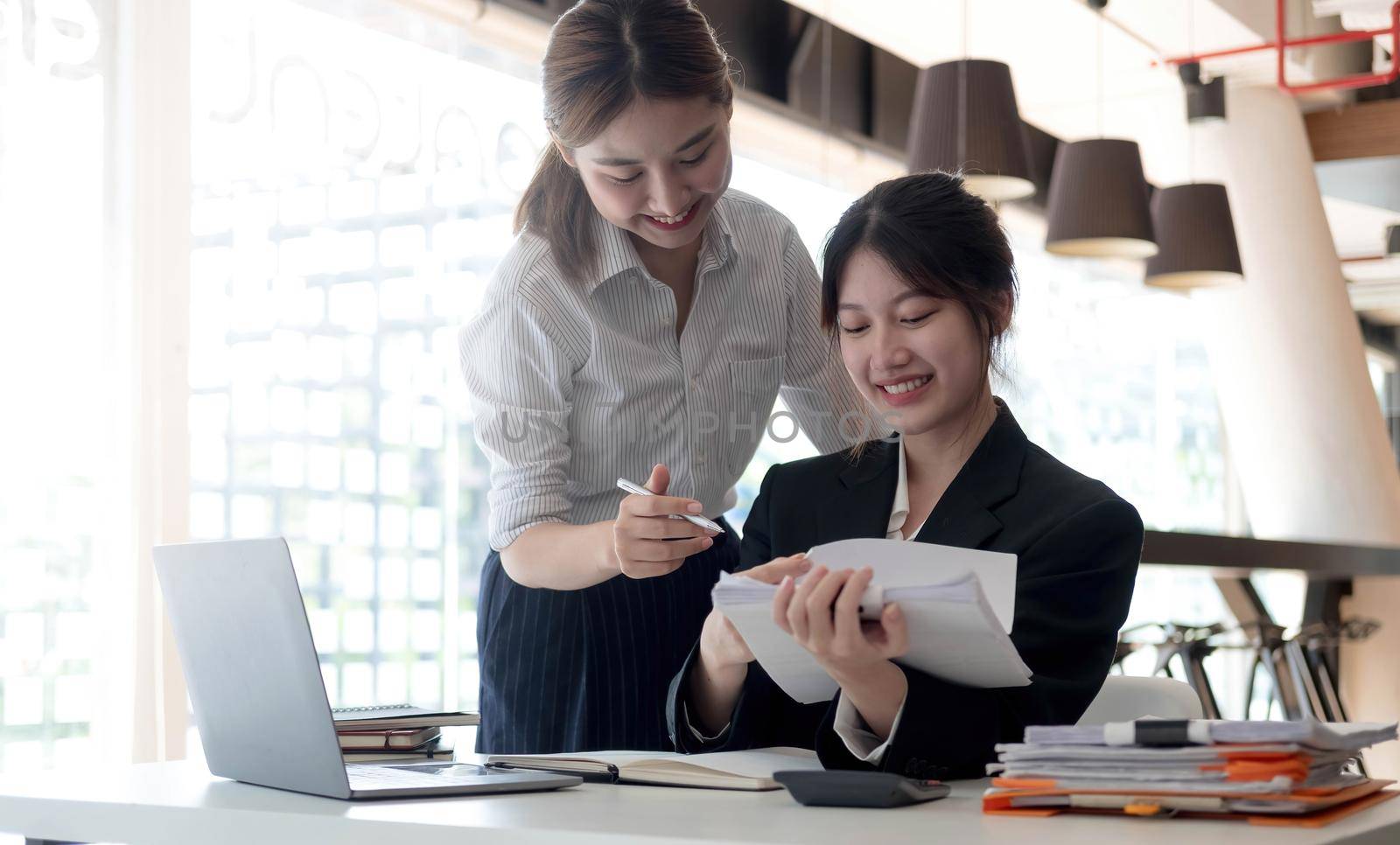 Two young asia business woman working together in office space by wichayada