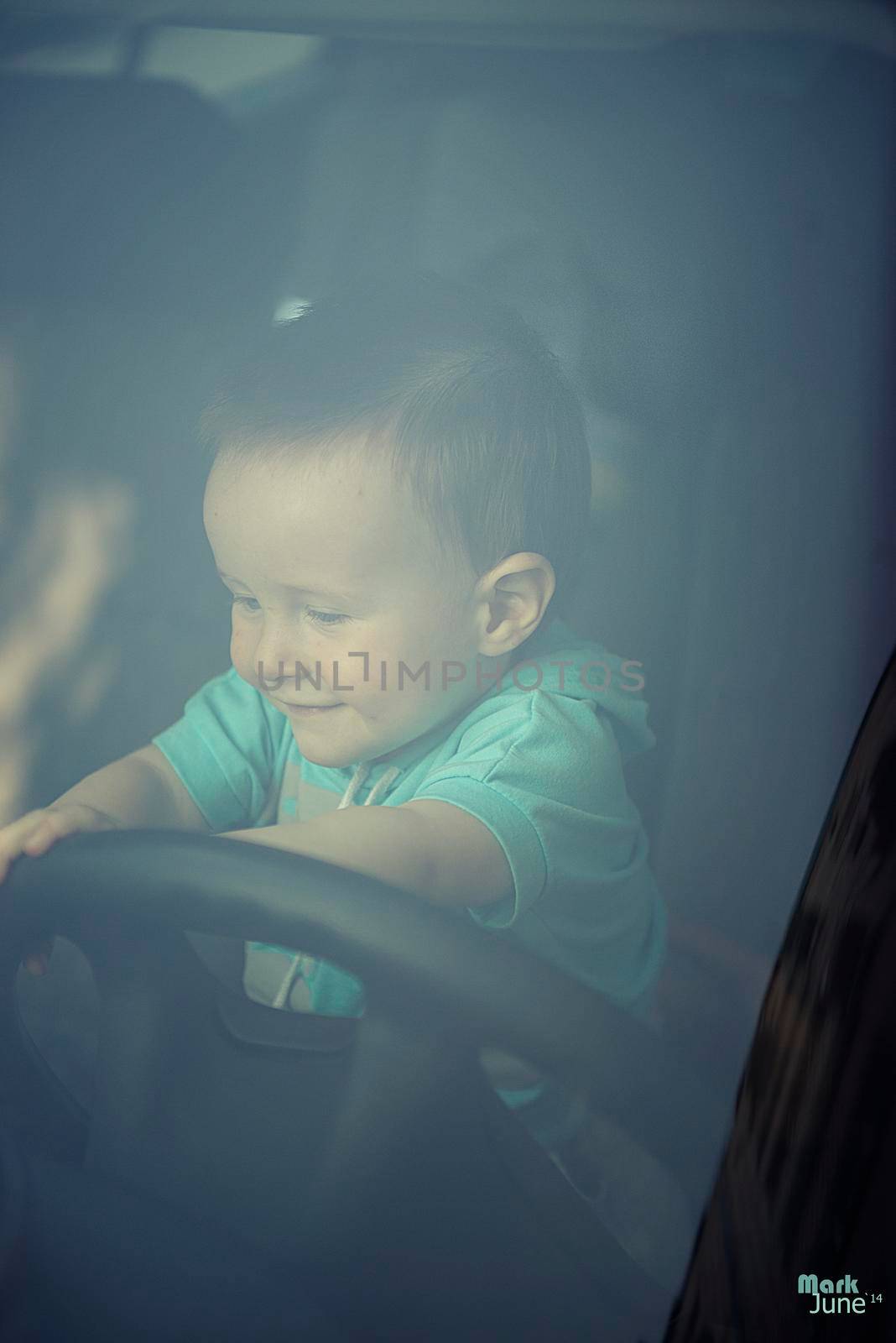 Little boy playing with a steering wheel in a car by marynkin