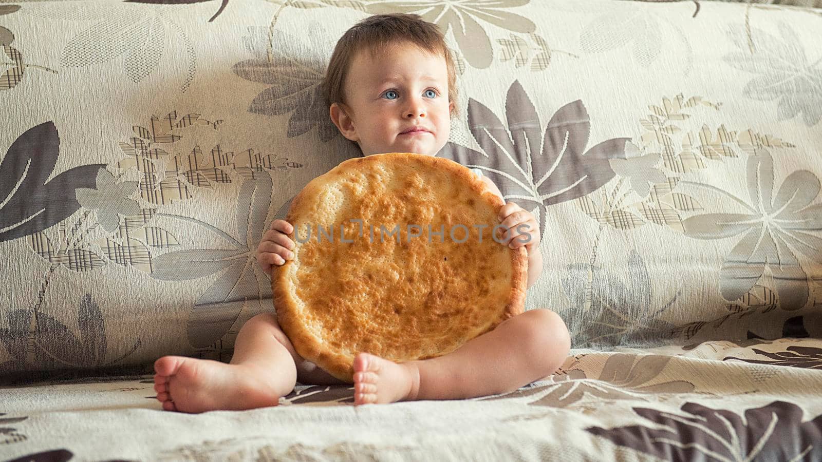 boy with uzbek cake on the couch at home.