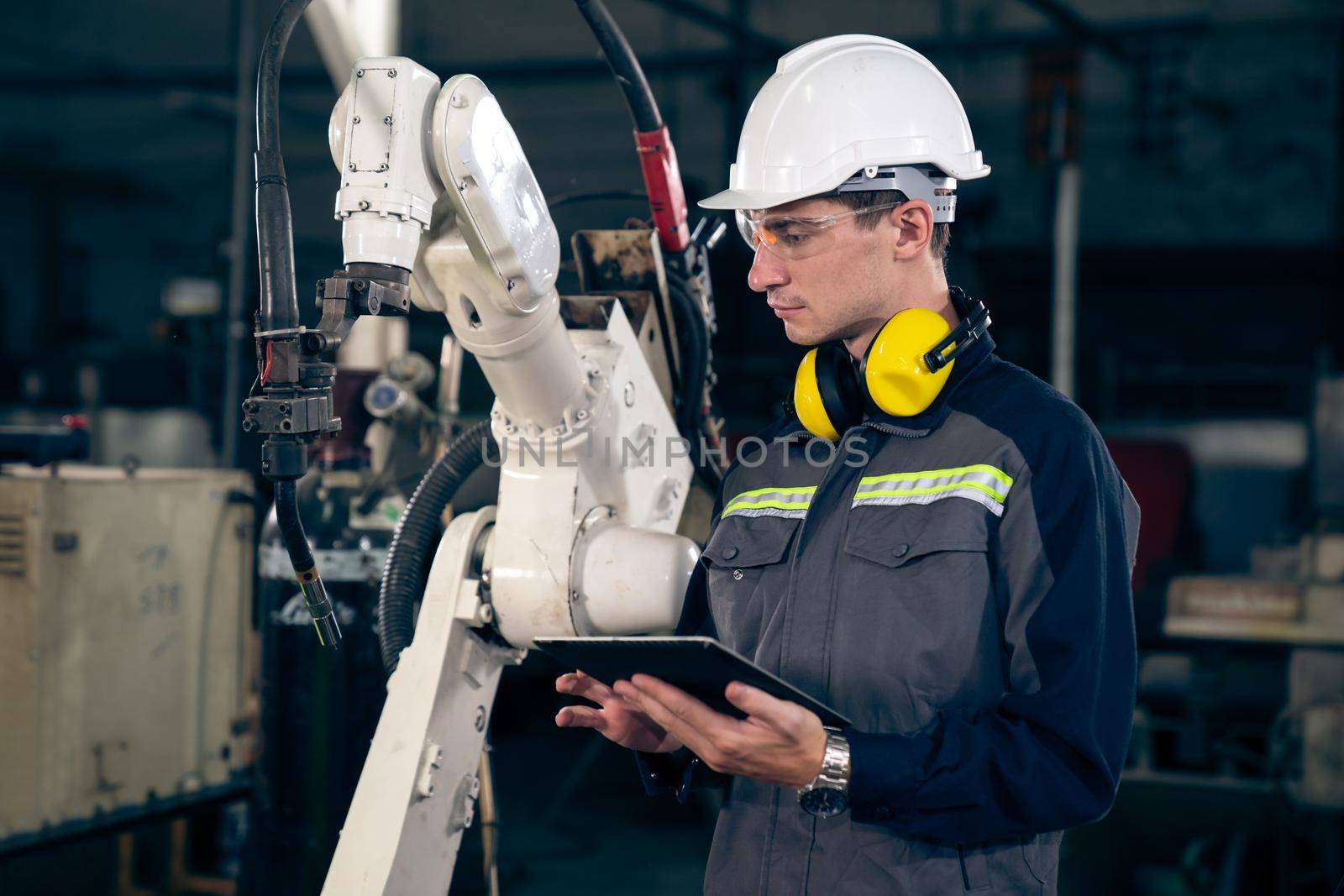 Young factory worker working with adept robotic arm in a workshop . Industry robot programming software for automated manufacturing technology .