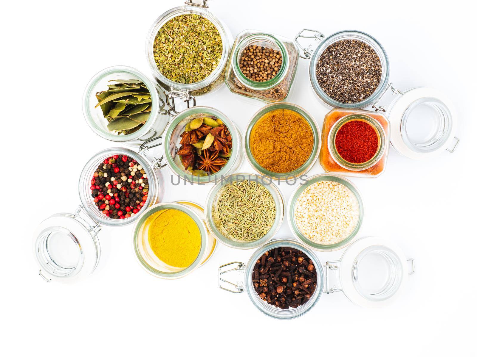 set of spices in glass jars on white background, top view. Paprika, curry, Bay leaf, anise and other seasonings.