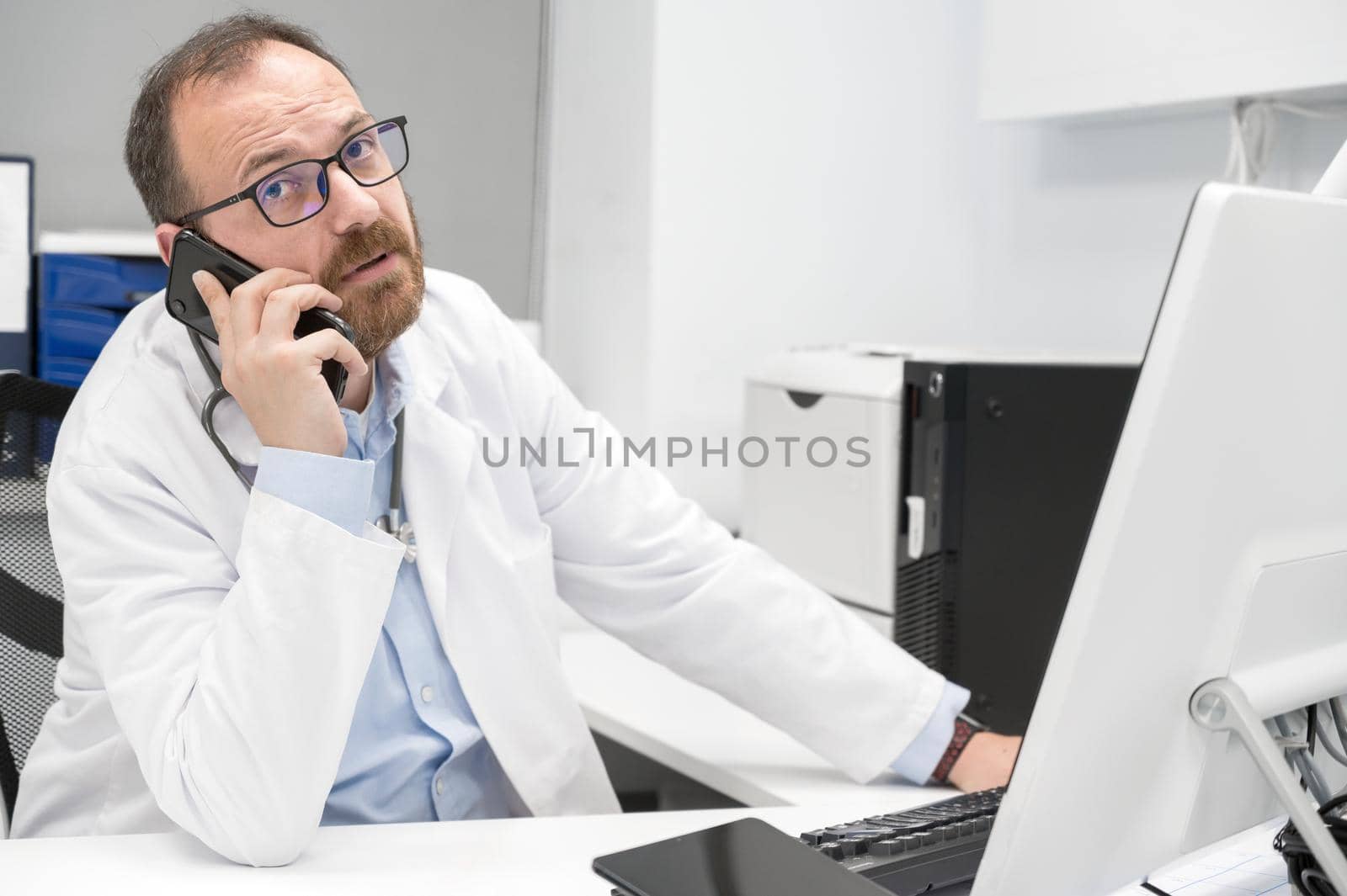 Doctor in office talking on phone by HERRAEZ