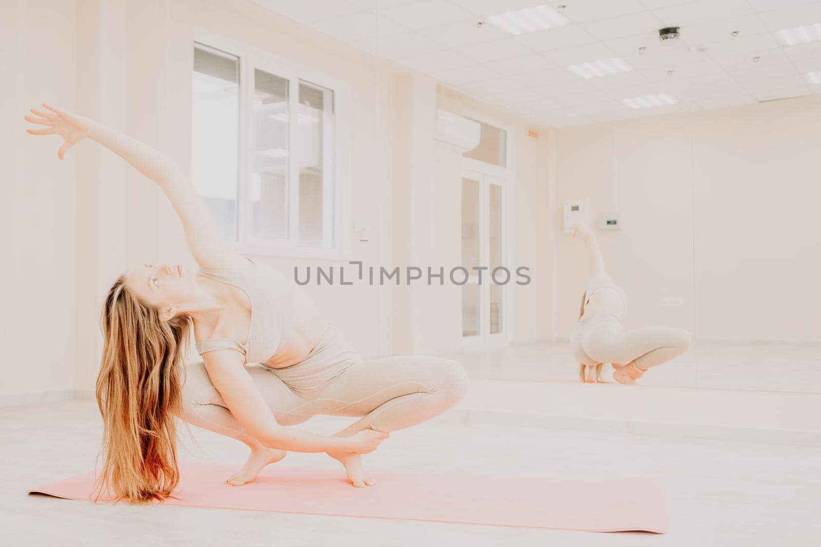 Group of young womans fitness instructor in Sportswear Leggings and Tops, stretching in the gym before pilates, on a yoga mat near the large window on a sunny day, female fitness yoga routine concept.