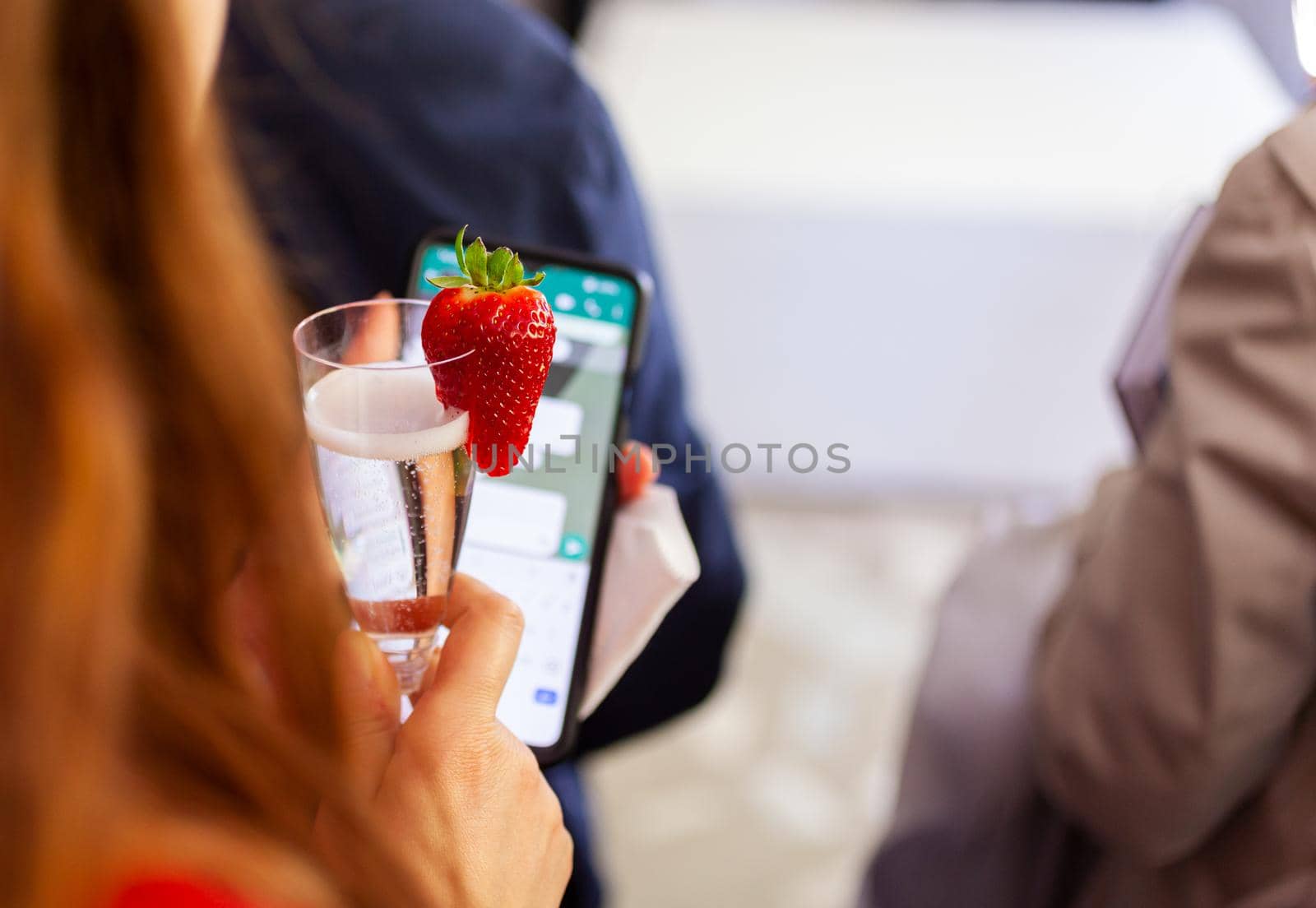 Drinking a prosecco white wine with Strawberry decor while using a smartphone
