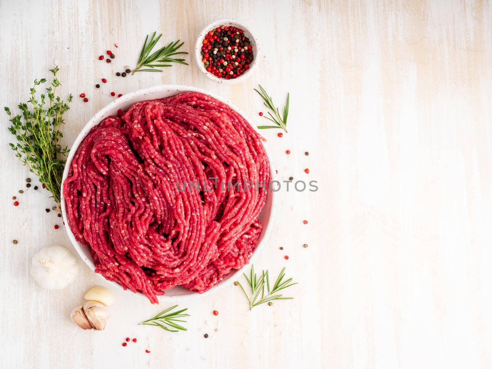 Mince beef, ground meat with ingredients for cooking on white wooden rustic table, top view, copy space