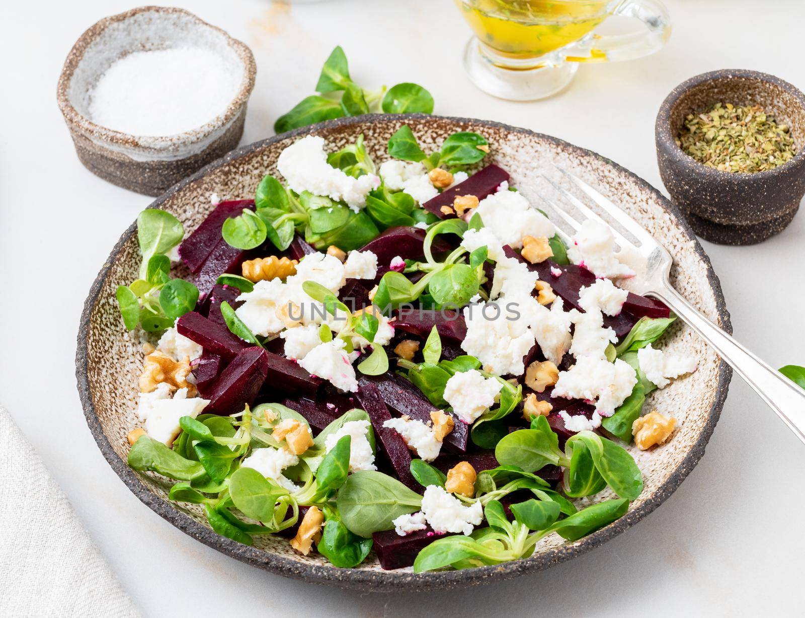 beetroot salad with feta, cheese, walnuts, corn salad on white table, side view