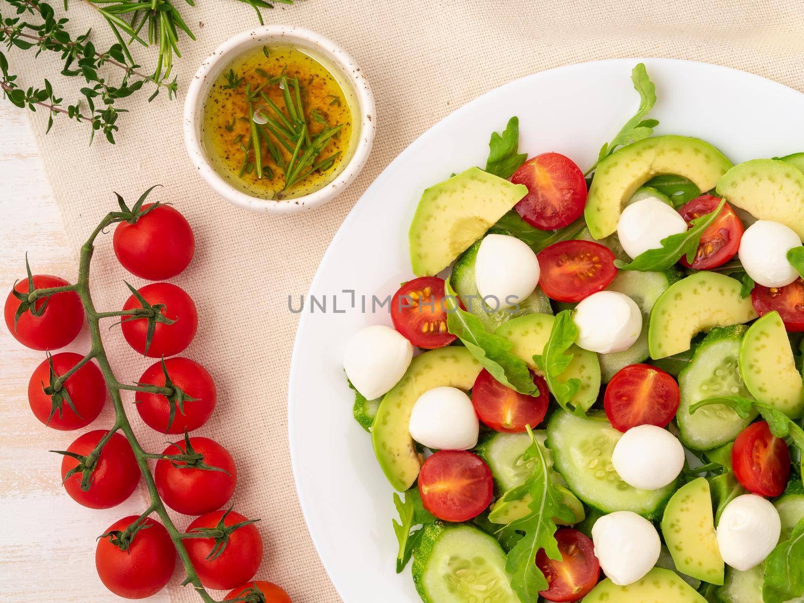 Fresh salad. Tomatoes, cucumbers, arugula, mozzarella, avocado. Fragrant oil with rosemary by NataBene