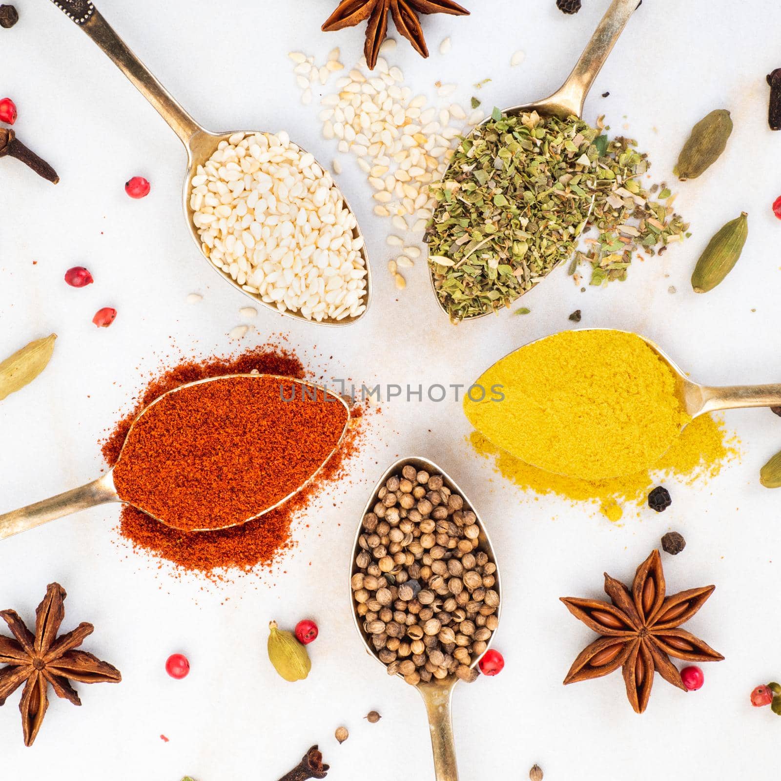 Set of spices in spoons on white background, top view. Paprika, curry, Bay leaf, anise and other seasonings, flat lay.