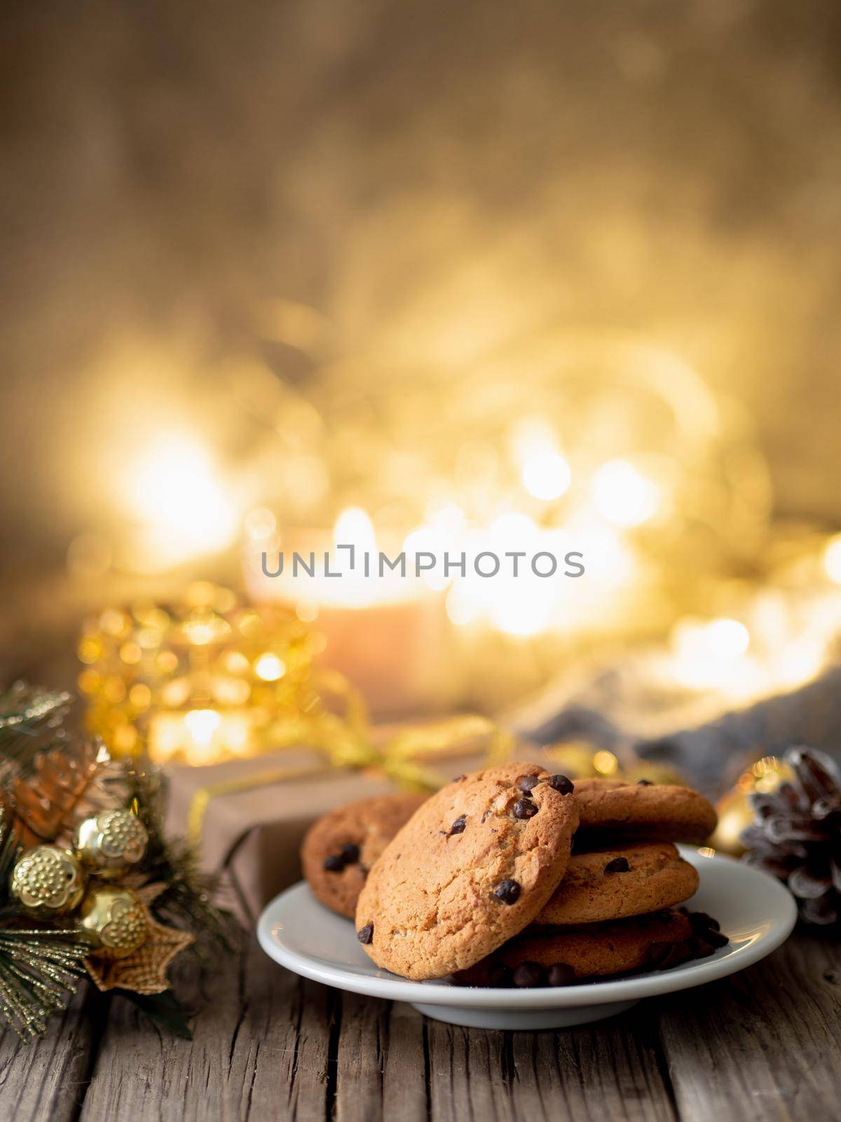 Chocolate chip cookies on dark christmas background. Cozy evening, Christmas decorations, candles and lights garlands