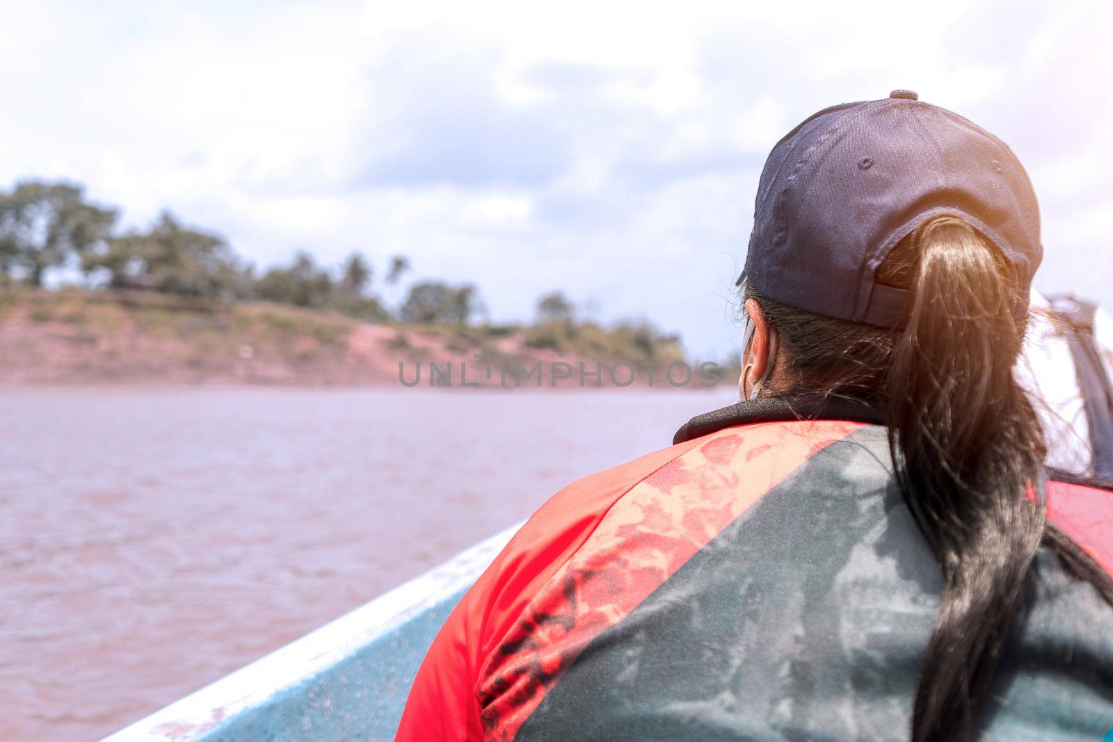 Latin brunette plus size woman from de the back traveling by boat down a muddy river in an indigenous community in Nicaragua, Central America.