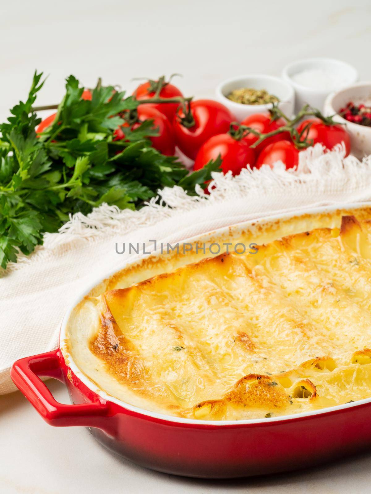 Cannelloni with filling of ricotta and parsley, baked with b chamel sauce, side view, vertical, white marble background by NataBene