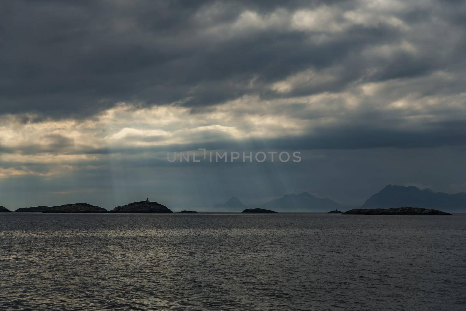Norwegian seascape, rocky coast with dramatic skies, the sun breaks through the clouds, sheer cliffs, small islands illuminated by the sun. High quality photo