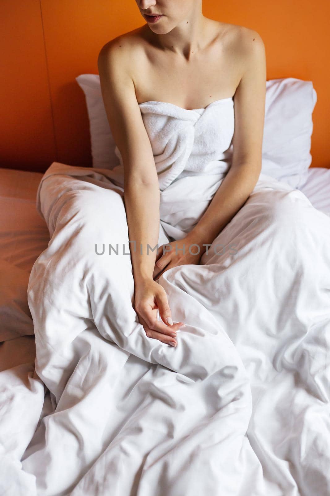 Young girl with clean skin with a towel on her head, lying in bed, resting after a shower, relaxing at home. Close-up