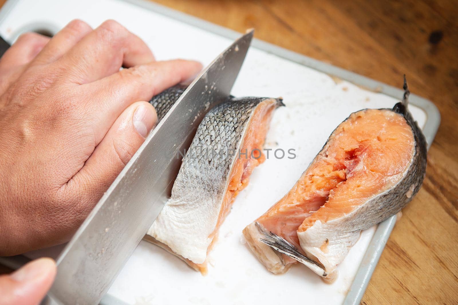 The cook cuts the fresh salmon with a sharp steak knife. Eating style for good health. by sfinks