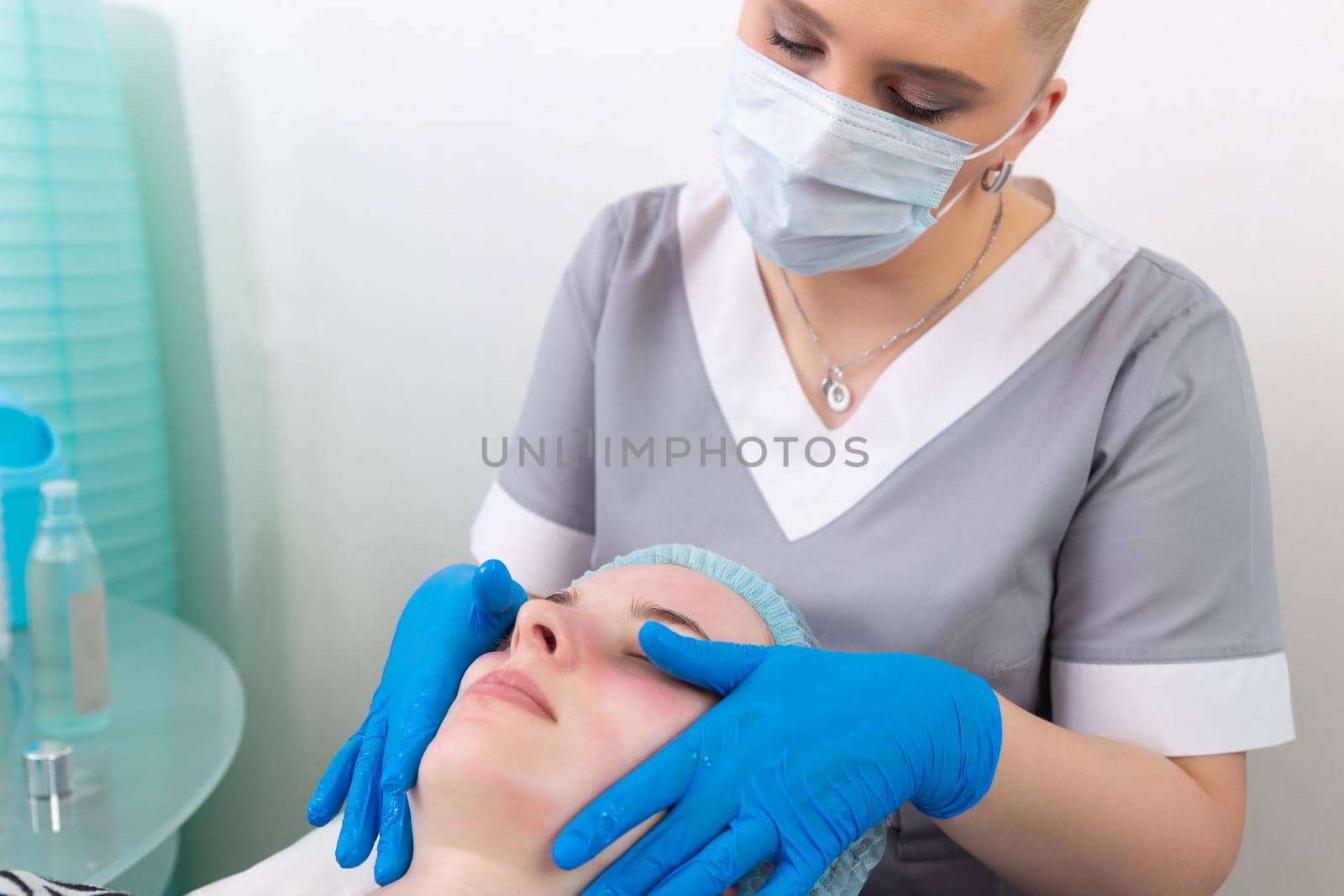 A female cosmetologist manually treats the patient's skin with a moisturizing and toning gel. The procedure helps to control the balance of fat content, restores the pH balance of the skin, gives a feeling of freshness and softness.