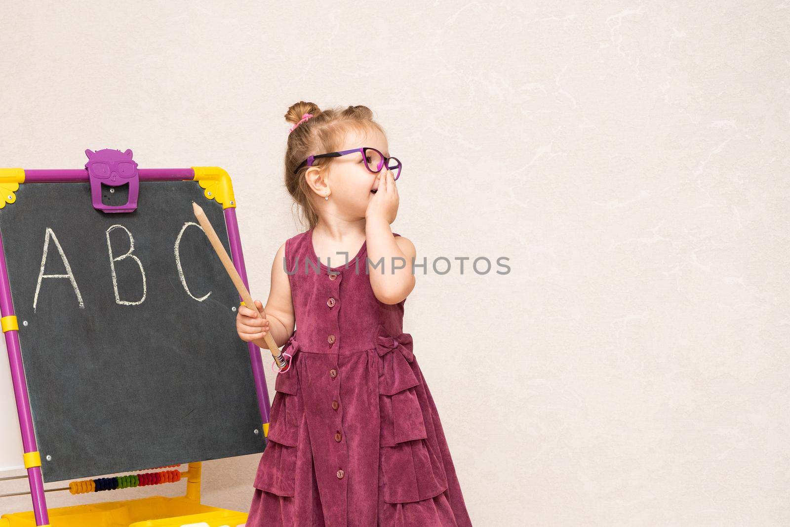 a girl in a dress and glasses near the blackboard shows students the letters in the alphabet by olex