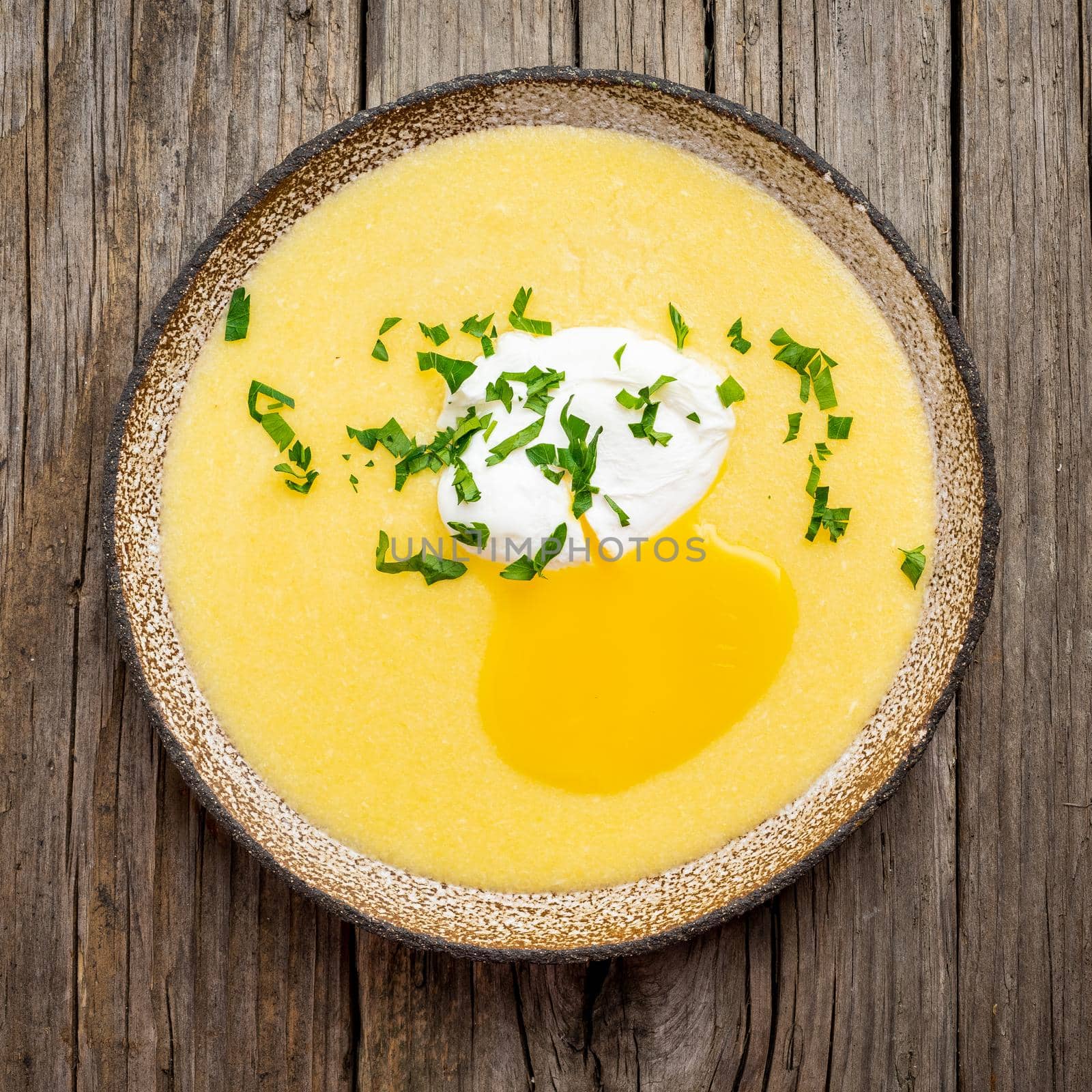 Polenta, porridge with Parmesan cheese and poached egg, on old dark wooden background, top view. traditional Italian cuisine
