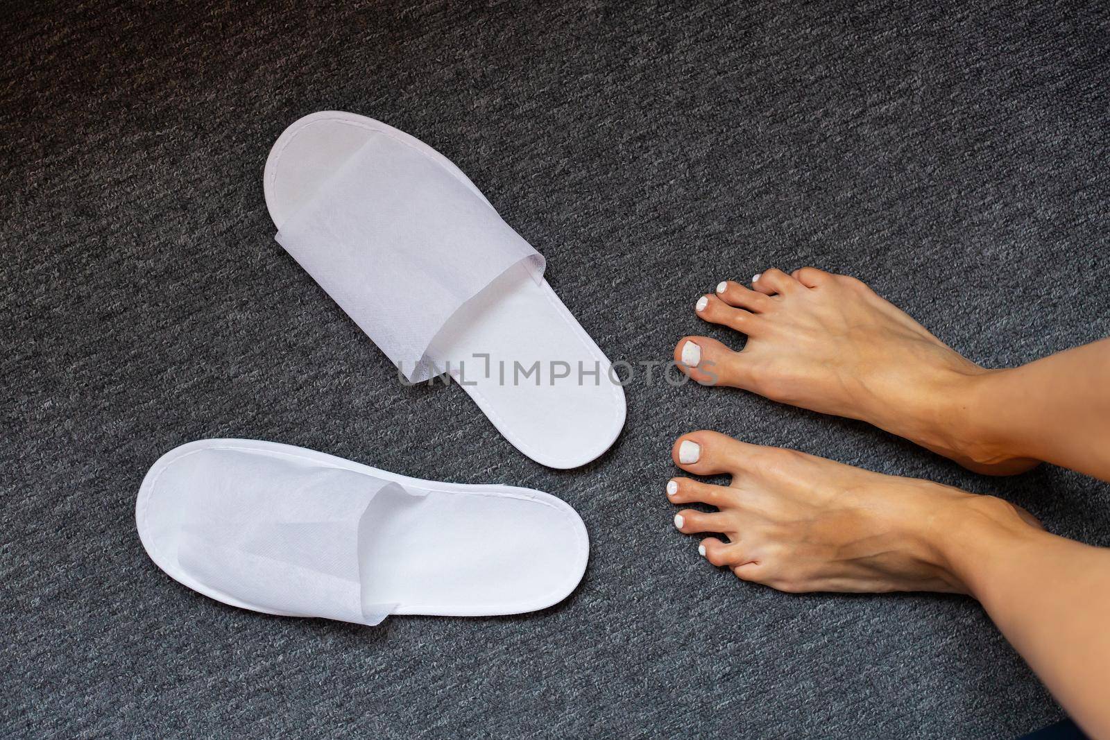 Comfortable and cozy white slippers on the rug, hotel accessories, top view