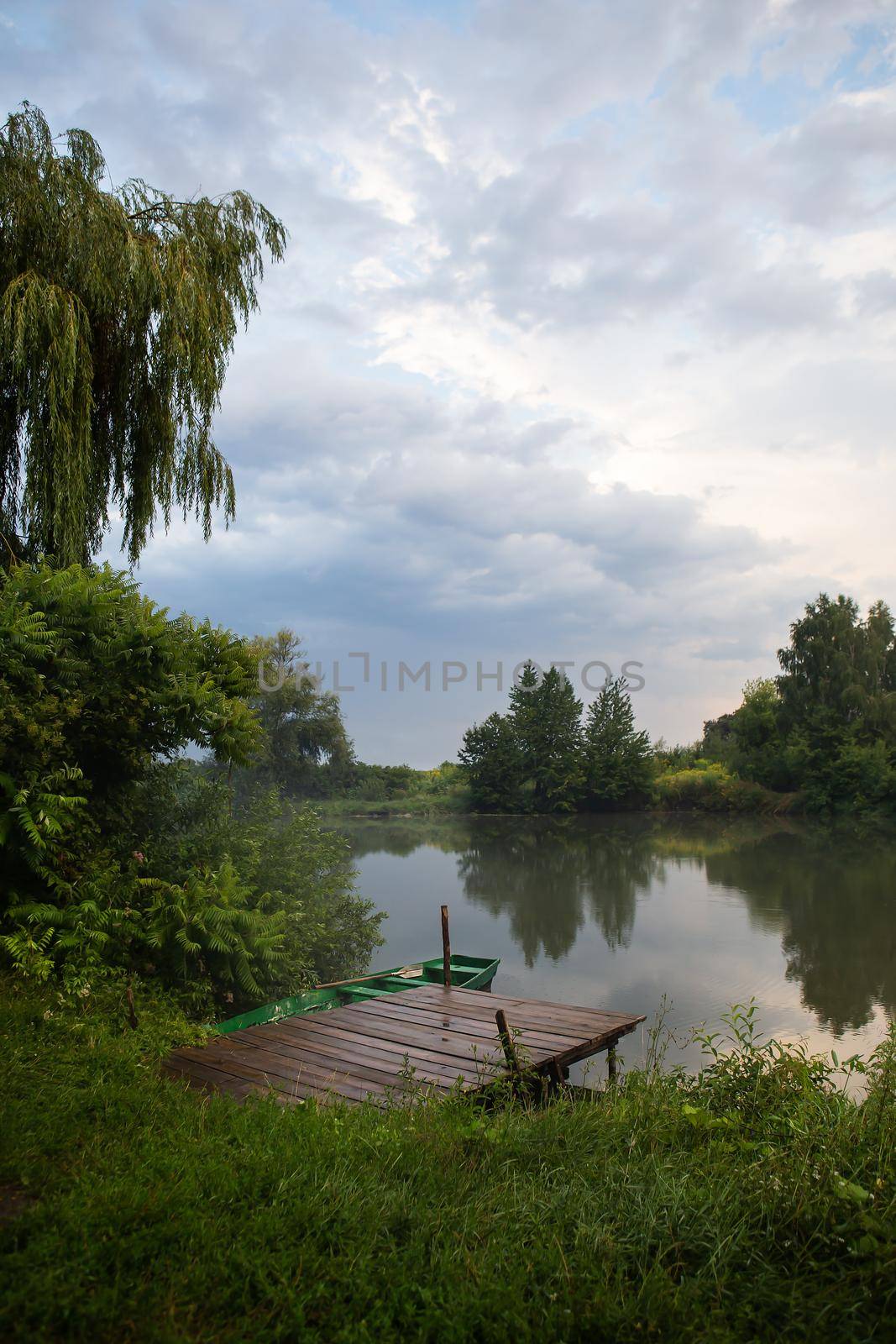 Wildlife, pier with a boat with oars. The sky after the rain, freshness in the air. The concept of camping and country rest with tents