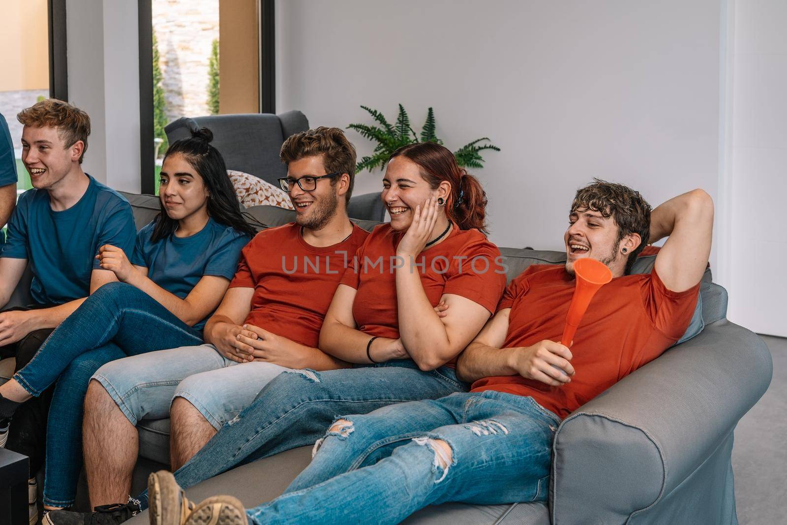 friends enjoying together their favourite sport broadcast on television competing for their team. group of youngsters partying