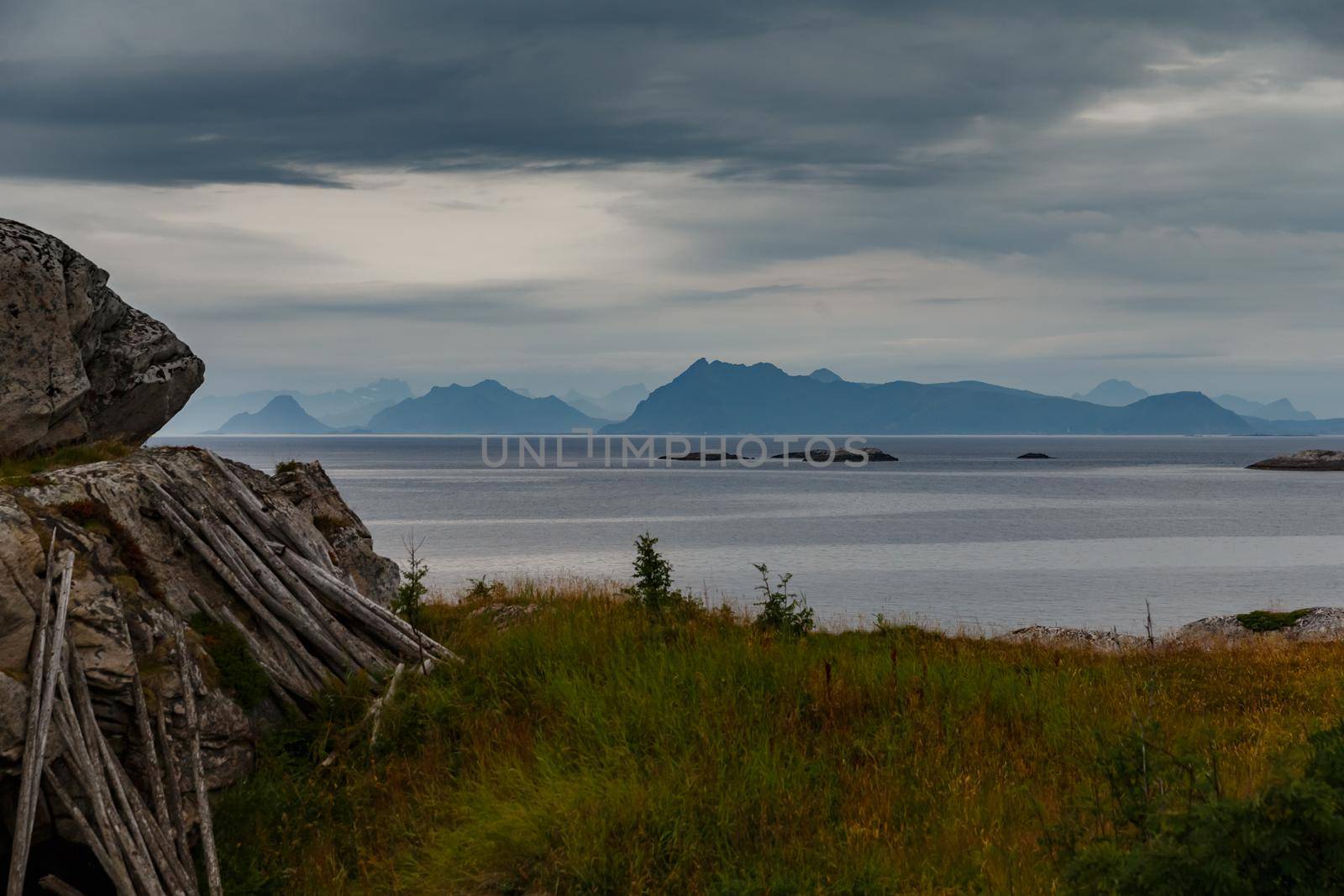 Norwegian seascape, rocky coast with dramatic skies, the sun breaks through the clouds, sheer cliffs, small islands illuminated by the sun. High quality photo