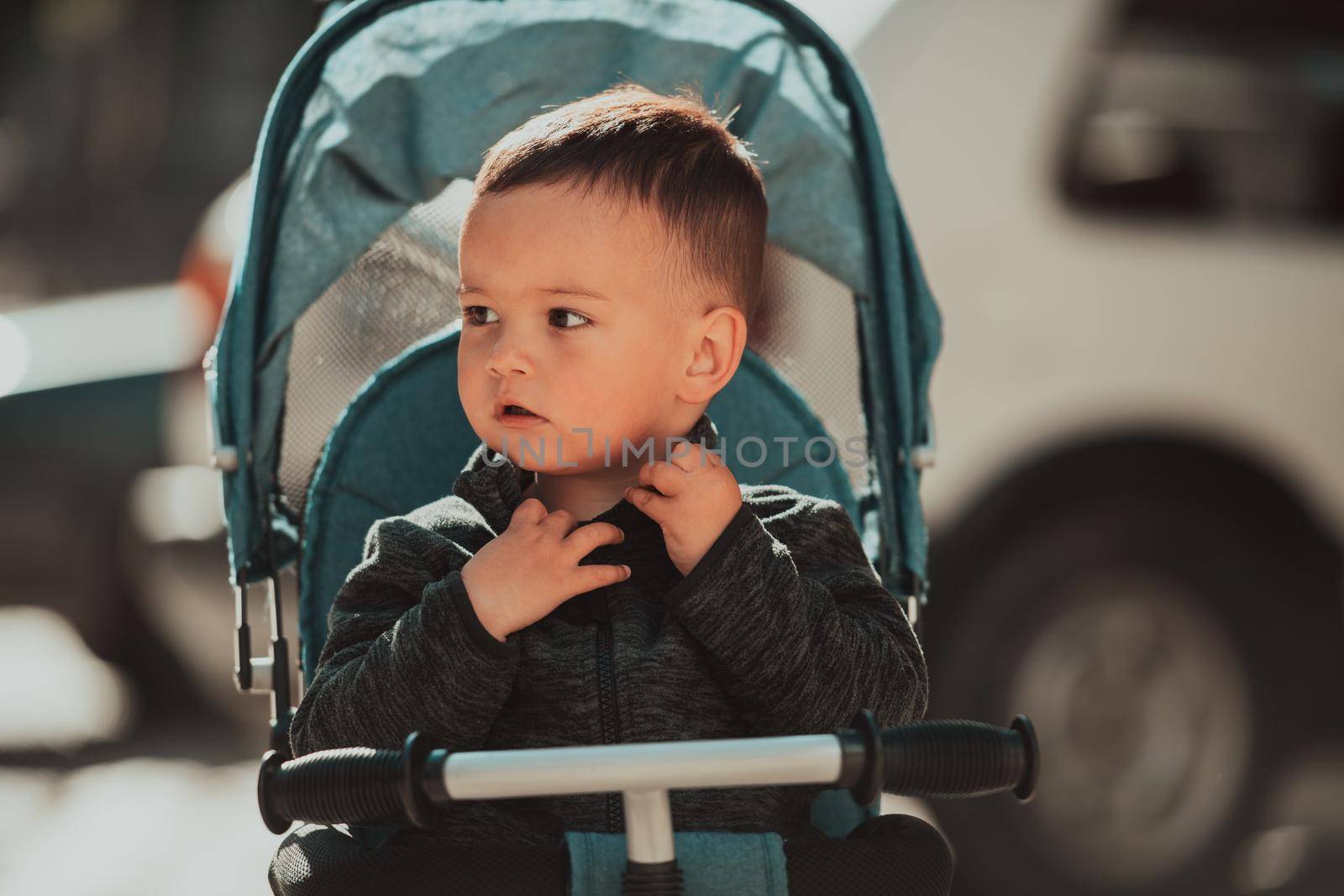 Sweet baby boy tow years old in a stroller bicycle outdoors. Little child in a pram. Infant kid in a pushchair. Spring walks with kids. High quality photo