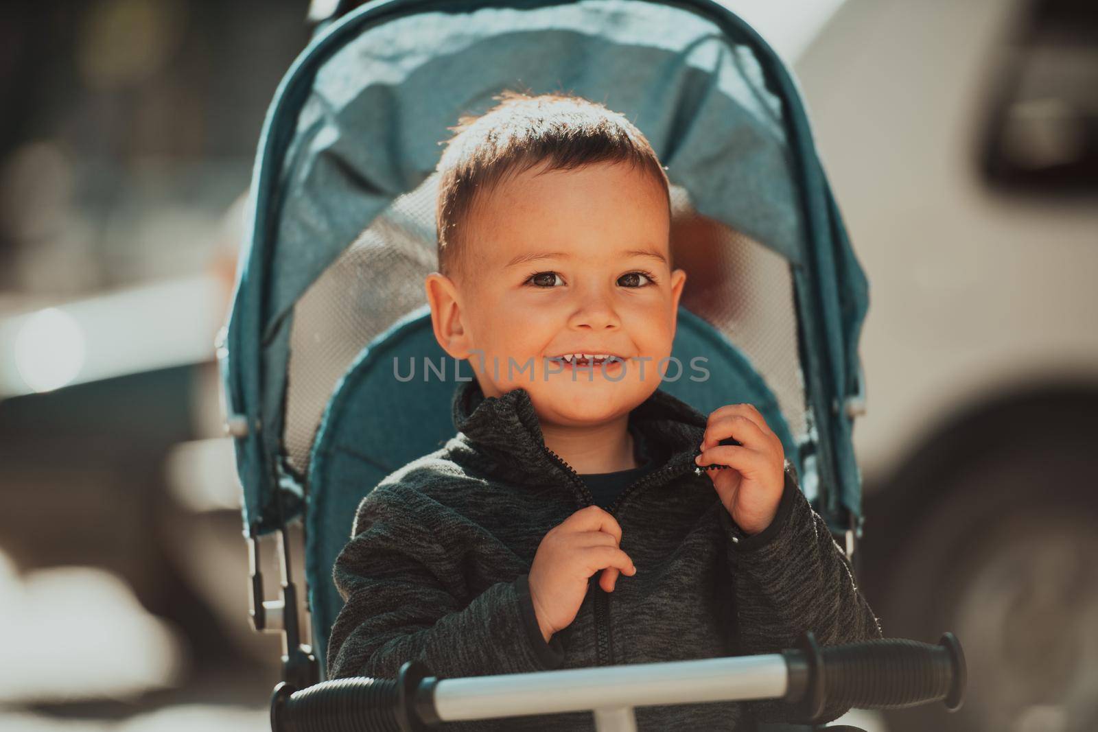 Sweet baby boy tow years old in a stroller bicycle outdoors. Little child in a pram. Infant kid in a pushchair. Spring walks with kids. High quality photo