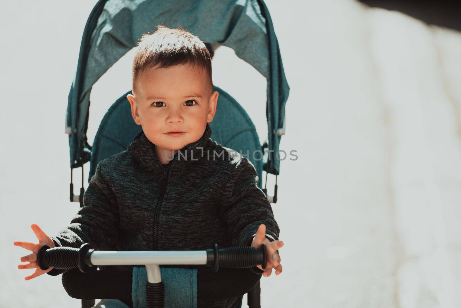 Sweet baby boy tow years old in a stroller bicycle outdoors. Little child in a pram. Infant kid in a pushchair. Spring walks with kids. High quality photo