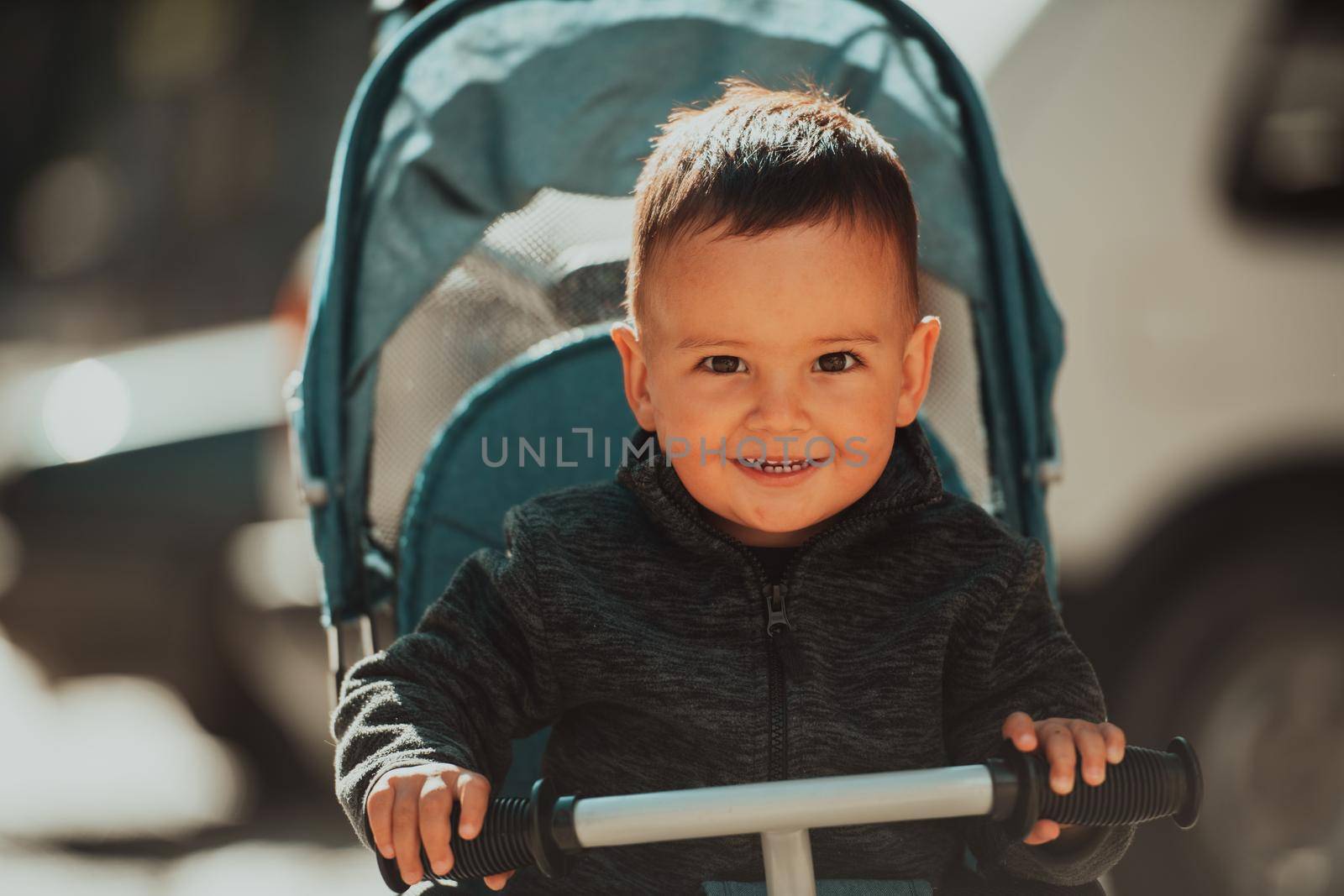 Sweet baby boy tow years old in a stroller bicycle outdoors. Little child in a pram. Infant kid in a pushchair. Spring walks with kids. High quality photo