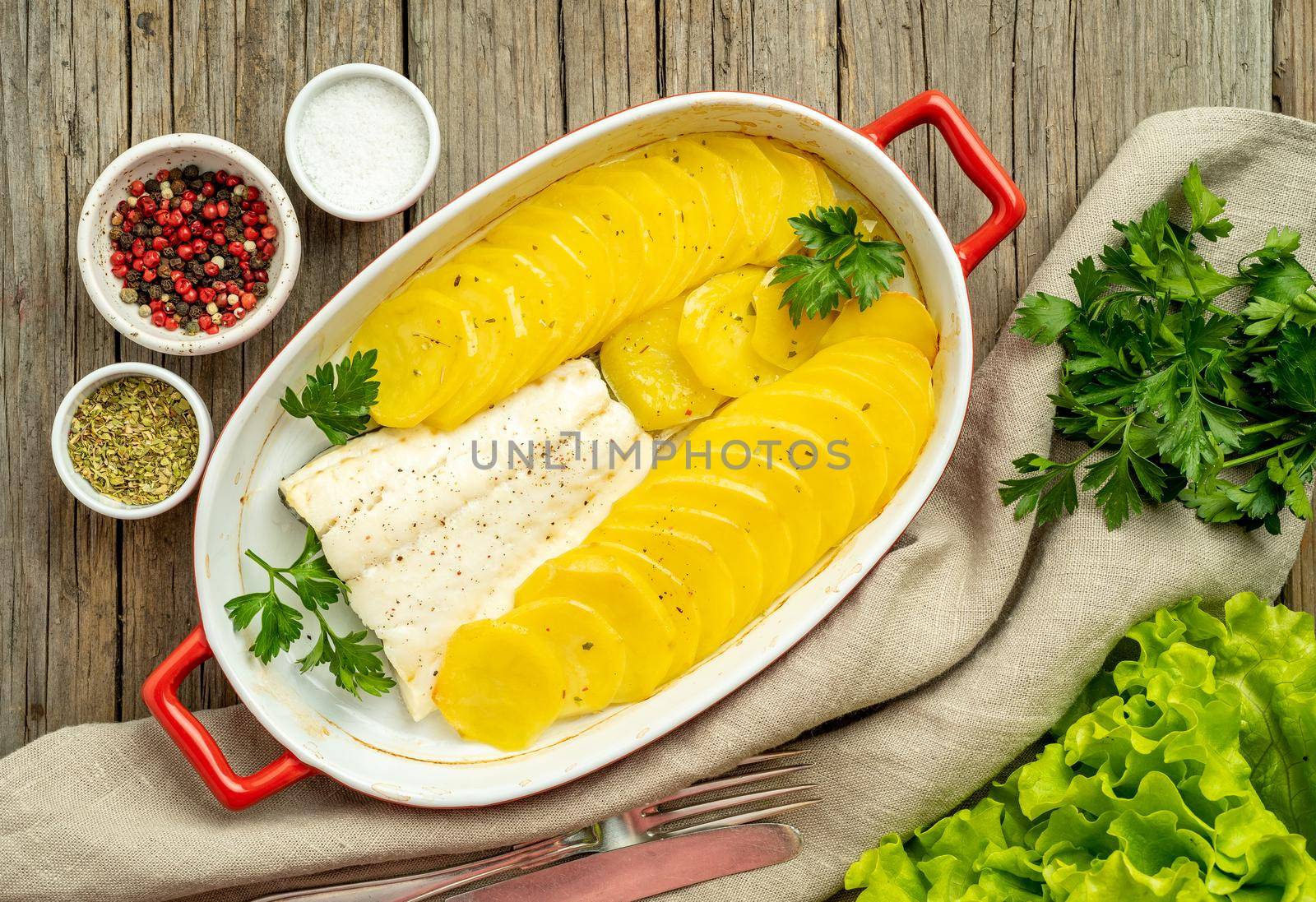 Fish cod baked in oven with potatoes and spice - healthy diet food. Dark wooden brown background, top view. by NataBene