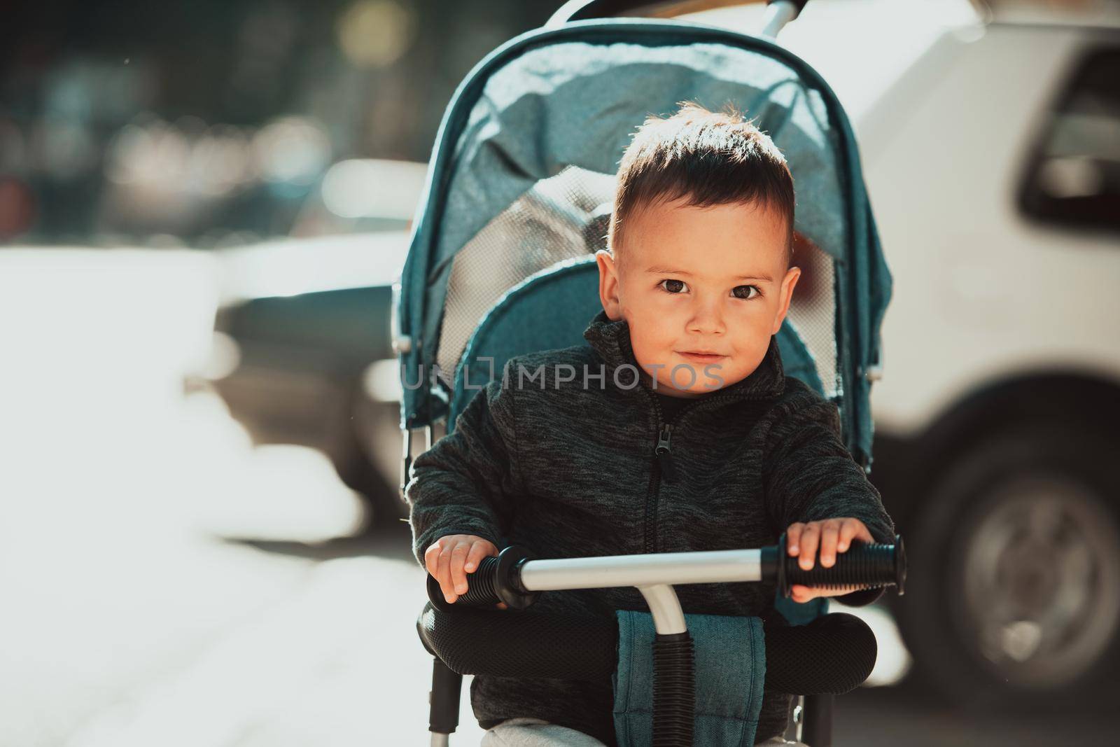 Sweet baby boy tow years old in a stroller bicycle outdoors. Little child in a pram. Infant kid in a pushchair. Spring walks with kids. High quality photo