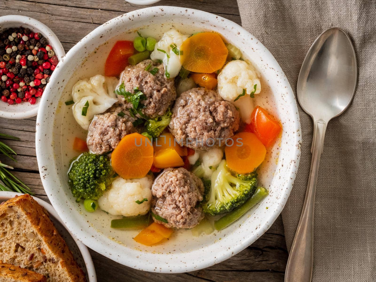 meatballs soup in white plate on old wooden rustic grey table, top view by NataBene