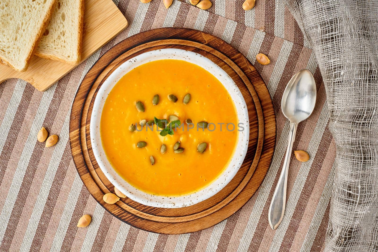 Pupmkin cream soup puree, Dietary vegetarian food on dark brown wooden table, top view, close up. by NataBene