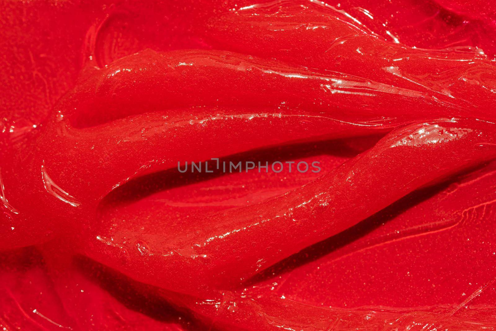 Red gel texture. Cosmetic clear liquid cream smudge. Skin care product sample closeup. Toothpaste or wax by photolime