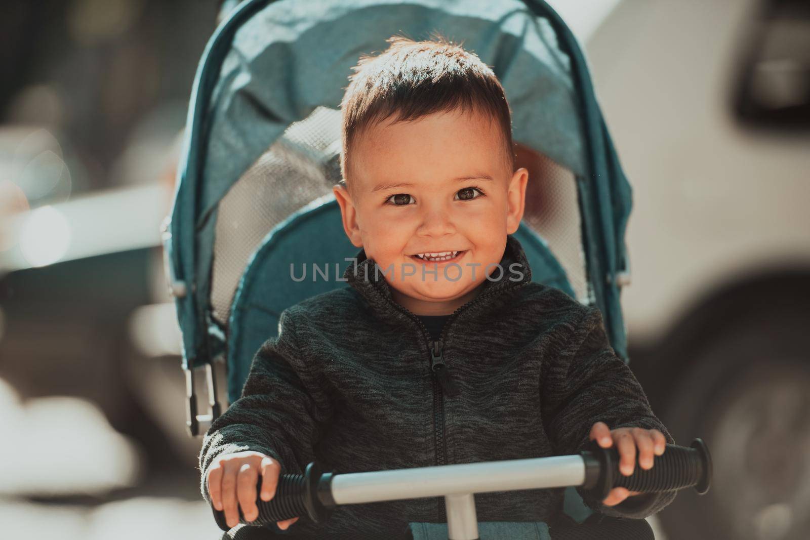 Sweet baby boy tow years old in a stroller bicycle outdoors. Little child in a pram. Infant kid in a pushchair. Spring walks with kids. High quality photo