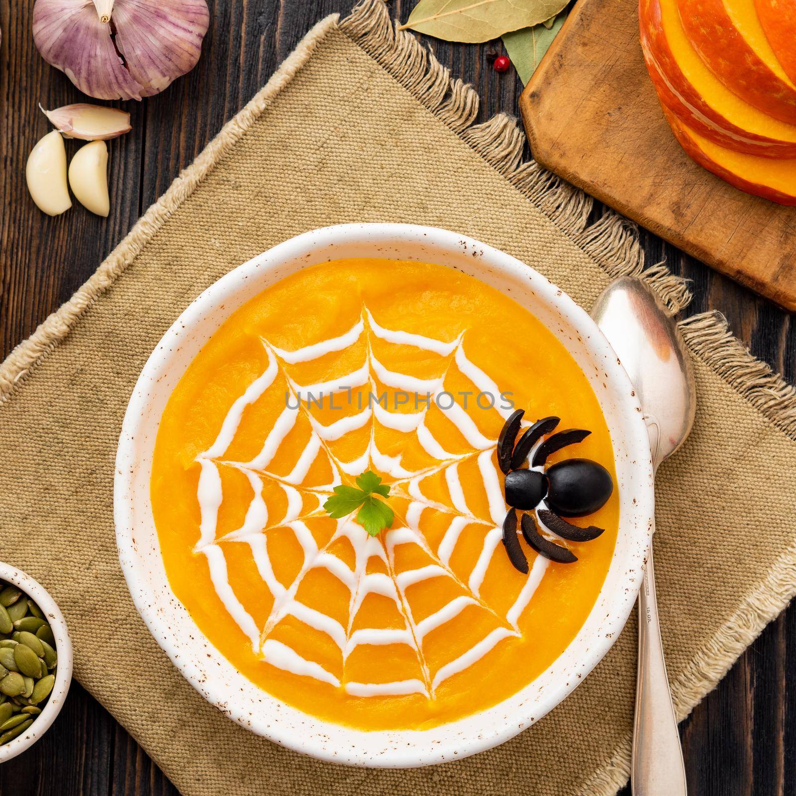 Funny food for Halloween. Pumpkin puree soup, spider web, dark old wooden table, a top view.