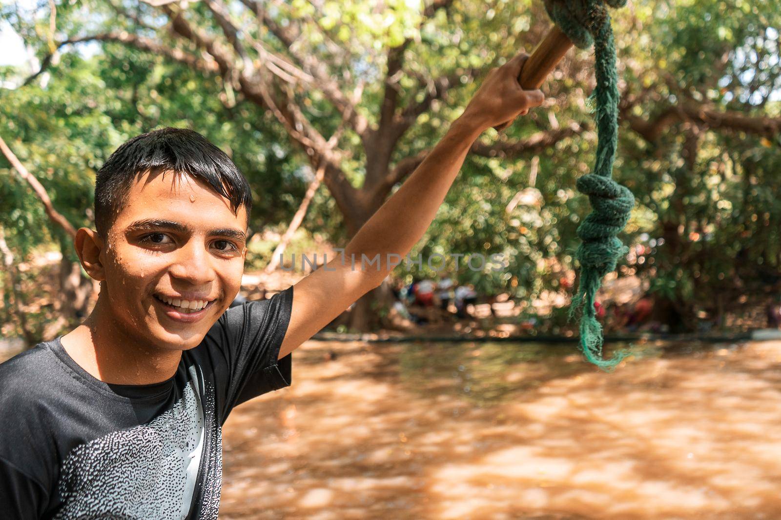Latin teen smiling and looking at camera holding a hand swing while having fun at a lake in the summer