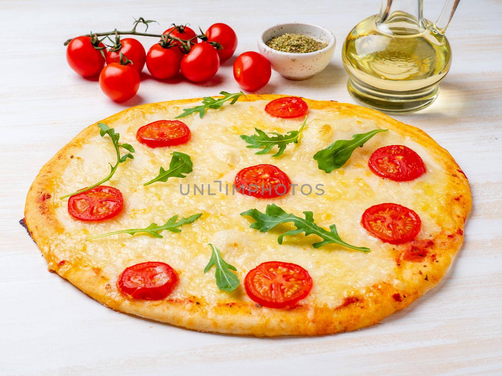 hot homemade Italian pizza margherita with mozzarella and tomatoes on white wooden table, side view.