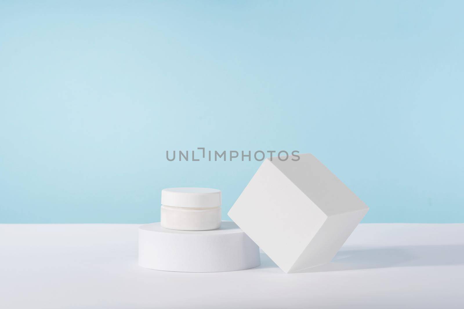 Cosmetic luxury cream jar bottle mockup on blue background on pedestal podium. Unbranded lotion beauty product packaging. Product presentation mock up. Lotion, mousse, cleanser for skincare routine