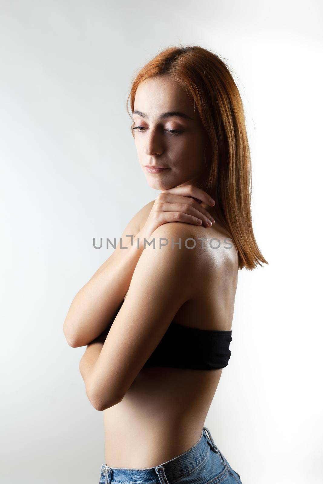 Beautiful girl with burnt orange hair posing in studio against gray background... by kokimk