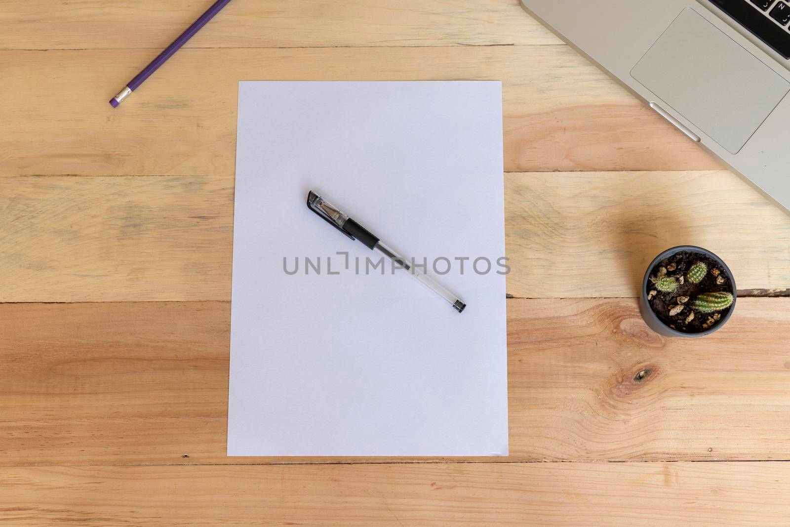 Blank A4 paper laying on a wooden office desk with supplies